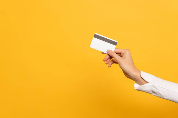 Cropped view of woman hand with credit card isolated on yellow