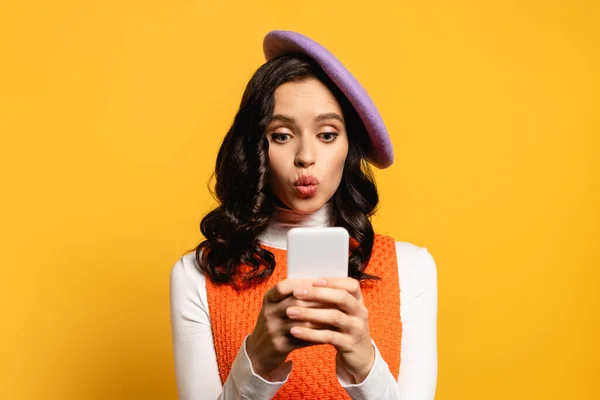 Brunette Woman Pouting Lips Wearing Beret Texting Smartphone Isolated Yellow — Stock Photo, Image