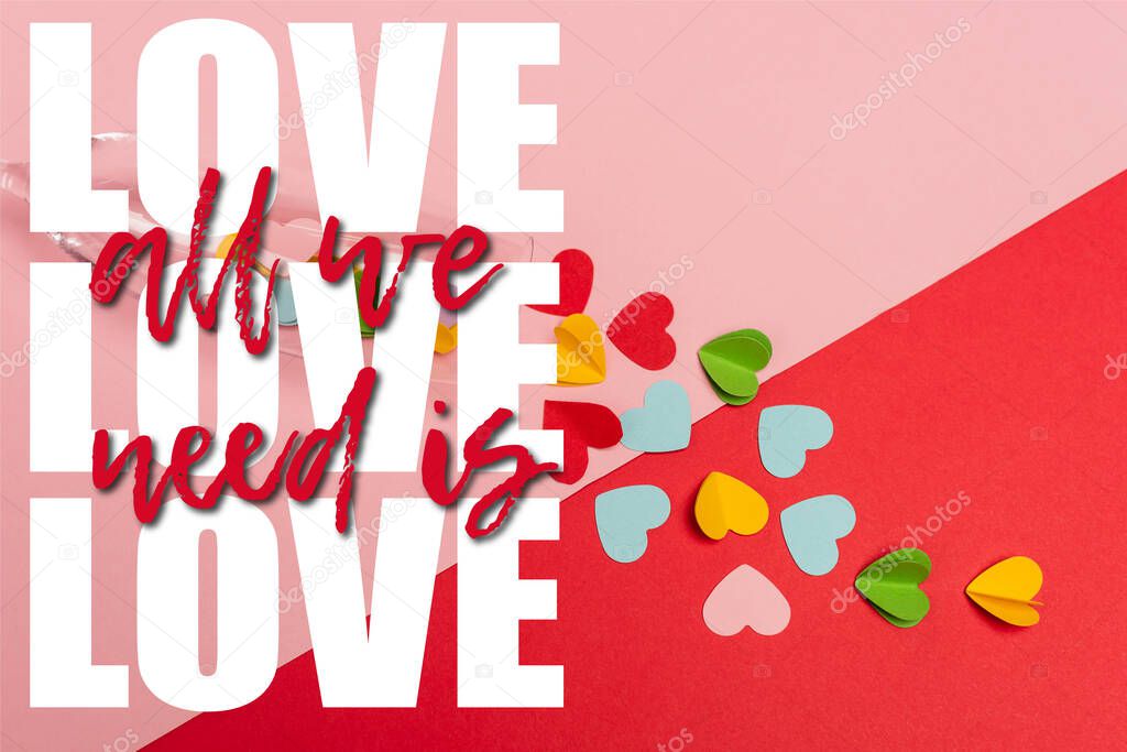 top view of champagne glass with colorful hearts near all we need is love lettering on pink and red