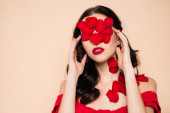 brünette junge Frau mit Rosenblättern im Gesicht isoliert auf rosa