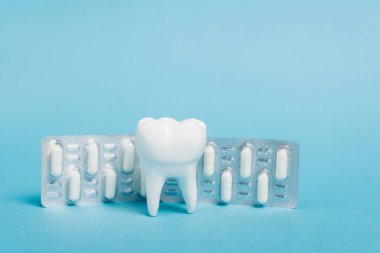 Mavi arka planda hapları olan su toplayan bir diş modeli.