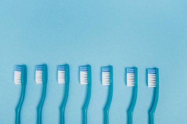 Top view of blue toothbrushes on blue background with copy space  clipart