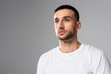 Kendine güvenen, esmer, beyaz tişörtlü, gri tişörtlü, yalnız bir adam.