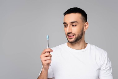 Beyaz tişörtlü neşeli İspanyol adam elinde diş fırçası tutuyordu.