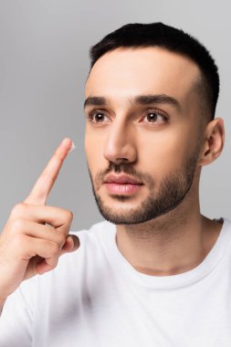 Esmer, ispanyol bir adam griye bakarken yüz kremi sürüyor.