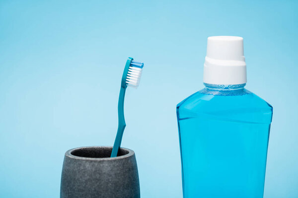 Зубная щетка и бутылка жидкости для полоскания рта на синем фоне
