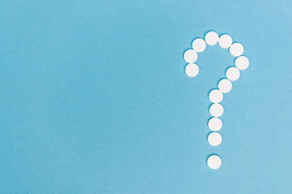 Top view of question mark from pills on blue background