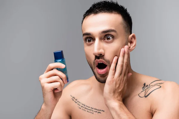 Shocked Hispanic Man Touching Face While Holding Bottle Aftershave Lotion — Stock Photo, Image