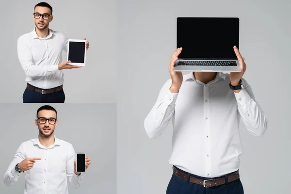 スマートフォンで指を指差してデジタルタブレットを見せ灰色に隔離されたノートパソコンで顔を隠している — ストック写真