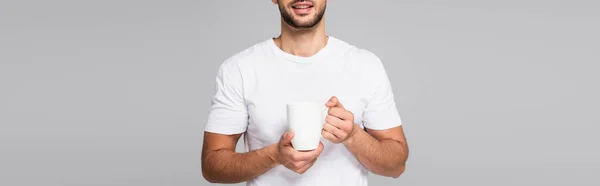 白いTシャツに身を包んだ男の笑顔の一部がグレーのバナーで区切られたカップを持ち — ストック写真