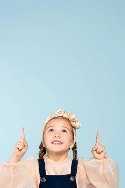 Smiling Kid Headband Bow Pointing Fingers While Looking Isolated Blue — Stock Photo, Image