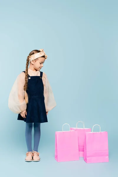 Piena Lunghezza Della Bambina Abito Guardando Borse Della Spesa Blu — Foto Stock