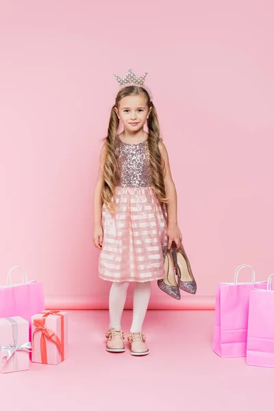 全身上下都是快乐的小女孩 穿着王冠 紧跟在礼物旁边 戴着粉色购物袋 — 图库照片