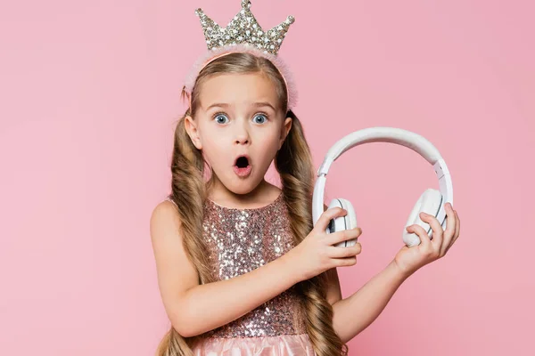 Wstrząśnięta Dziewczynka Koronie Trzyma Słuchawki Bezprzewodowe Izolowane Różowy — Zdjęcie stockowe