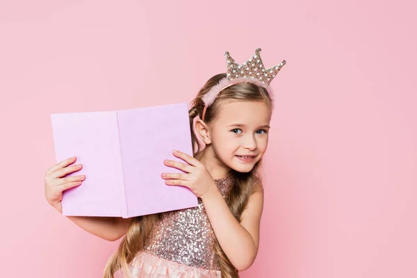 戴着王冠的快乐小女孩手里拿着一本粉红色的书 — 图库照片