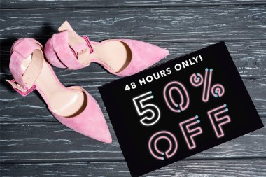 Tahta levhanın yanındaki pembe ayakkabıların sadece 48 saatlik görüntüsü ahşap yüzeydeki harflerde% 50 indirim var.