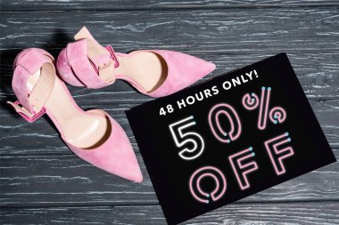 top view of pink shoes near placard with 48 hours only, 50 percent off lettering on wooden surface clipart