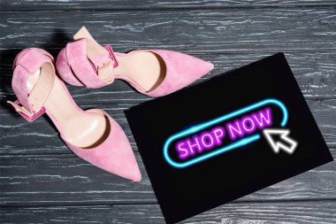 Tahta yüzey üzerinde neon dükkânı olan, plaketin yanındaki pembe ayakkabıların üst görüntüsü.