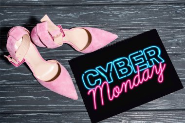 Tahta yüzeyinde neon siber pazartesi harfleri olan pembe ayakkabılar.