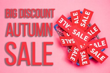 top view of sale tags in shopping basket near big discount autumn sale lettering on pink, black friday concept clipart