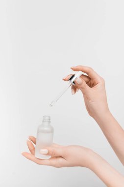 Kadının elinde serum ve pipetle beyaz şişeyi tutarken kısmi görüntüsü