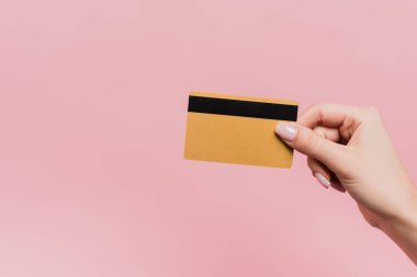partial view of woman holding credit card in hand isolated on pink clipart