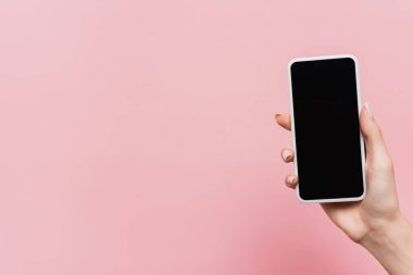 Elinde boş ekran olan akıllı telefonu pembe üzerine izole edilmiş bir kadın görüntüsü.