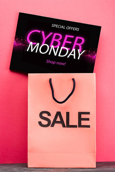 placard with special offers, cyber monday lettering near shopping bag on pink