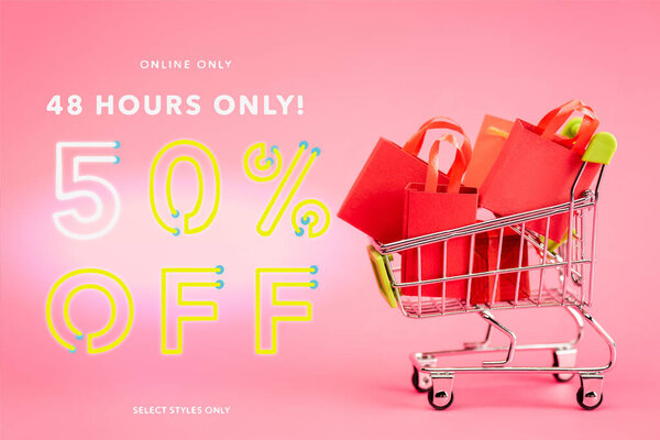 shopping bags in small trolley near online only, 48 hours only, 50 percent off, select styles only lettering on pink, black friday concept