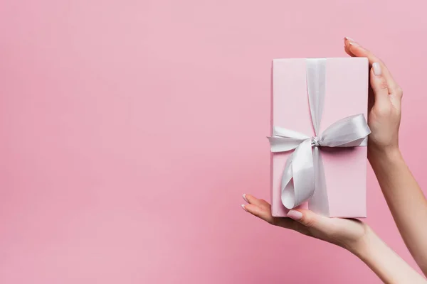 用粉红色隔离的手握住礼物的妇女的局部视图 — 图库照片