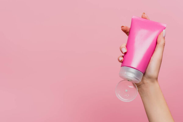 обрезанный вид женщины, держащей трубку с лосьоном изолированы на розовый