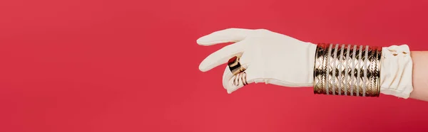 partial view of woman in glove with rings and bracelet isolated on red, banner