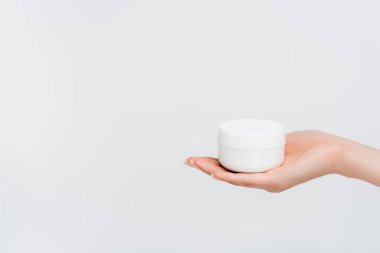 Beyaz üzerinde nemlendirici bulunan kavanozu tutan kadının kısmi görüntüsü