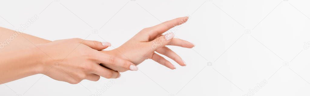 partial view of woman touching hand while applying hand cream isolated on white, banner