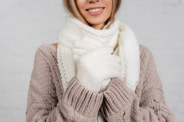 Beyaz arka planda sıcak süveter, eşarp ve eldiven giymiş gülümseyen kadın görüntüsü.