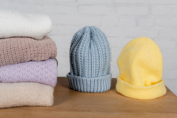 Warm hats and sweaters on wooden table on white background