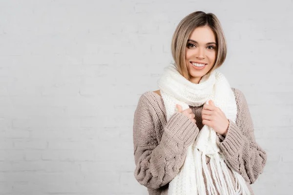 笑顔女性でニットセーターとスカーフ見ますカメラ上の白の背景 — ストック写真