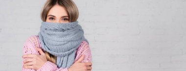 Young woman in sweater and scarf suffering from cold on white background, banner  clipart
