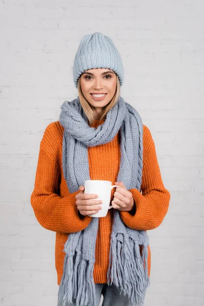 뜨개질 스웨터를 모자와 스카프를 여자가 배경에 미소를 — 스톡 사진