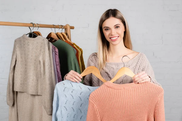 Young Woman Holding Hangers Warm Sweaters White Background — Stock Photo, Image