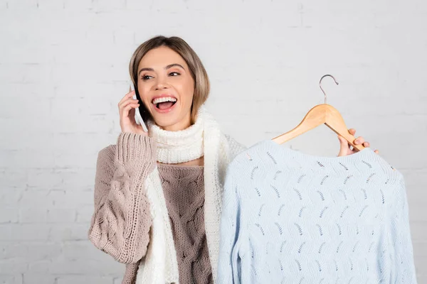 Cheerful Woman Warm Clothes Talking Cellphone Holding Hanger Sweater White — Stock Photo, Image