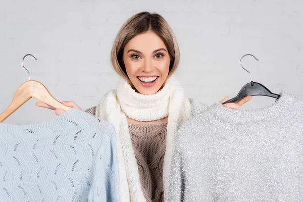 Cheerful Woman Holding Hangers Sweaters While Looking Camera White Background — Stock Photo, Image