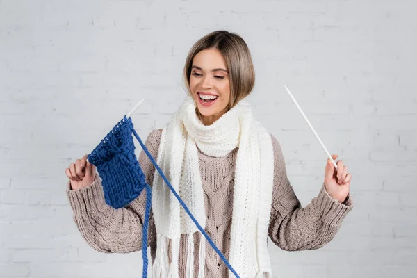 Positive Woman Scarf Sweater Holding Yarn Knitting Needles White Brick — Stock Photo, Image