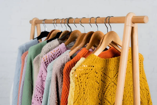 Hangers with colorful sweaters on hanger rack on white background