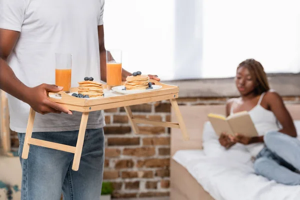 African American Man Holding Tray Breakfast Girlfriend Book Blurred Background — Stock Photo, Image