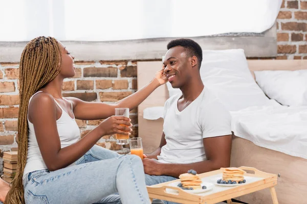 Mujer Afroamericana Con Vaso Jugo Naranja Tocando Novio Sonriente Cerca — Foto de Stock