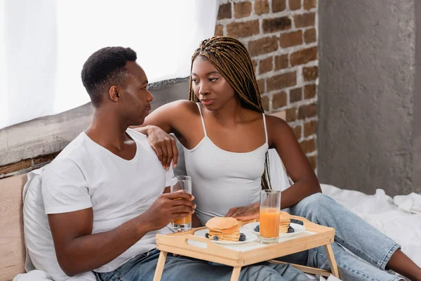 Mujer Afroamericana Mirando Novio Cerca Sabrosos Panqueques Jugo Naranja Bandeja — Foto de Stock