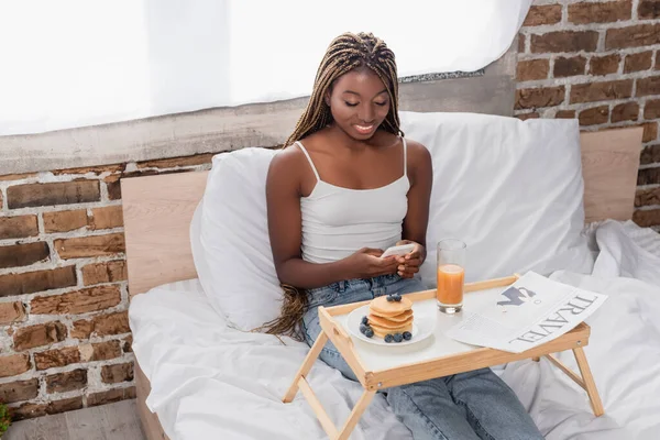 Smiling African American Woman Using Smartphone Breakfast Newspaper Tray Bed — Stock Photo, Image