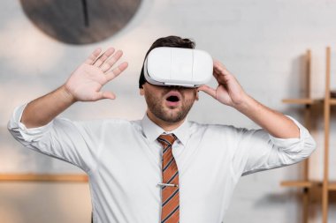 astonished architect gesturing while using vr headset in office clipart