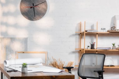 Mimarlık bürosundaki planlar ve rüzgar türbinleriyle dolu bir masa.